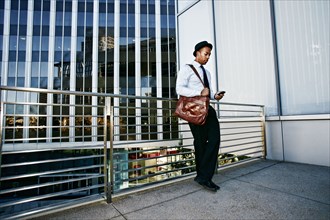 Black businessman using cell phone outside office building