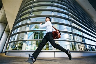 Black businessman running outside office building