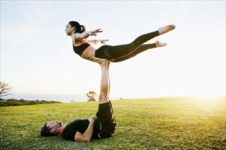 Caucasian couple doing acro yoga in park