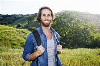 Caucasian hiker standing in grass on mountain