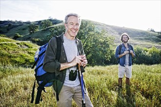 Caucasian hikers standing in grass on mountain