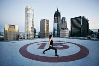 Caucasian woman stretching legs on urban rooftop