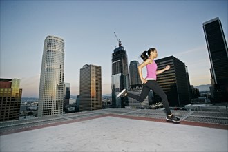 Mixed Race woman running on urban rooftop
