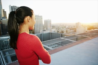 Mixed Race woman watching sunset on urban rooftop