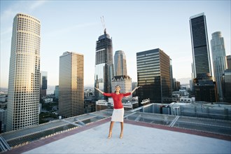 Mixed Race businesswoman celebrating on urban rooftop