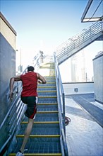 Caucasian man running up staircase on urban rooftop