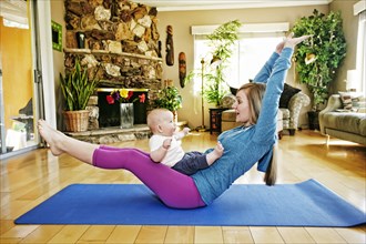 Mother working out on exercise mat with baby in lap