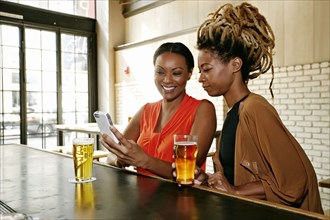 Black women using cell phone at bar
