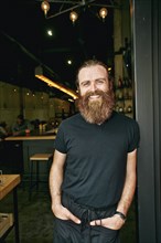 Smiling Caucasian man with beard leaning in doorway
