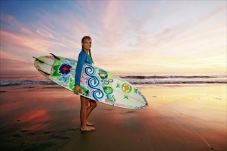 Caucasian woman carrying surfboard at beach