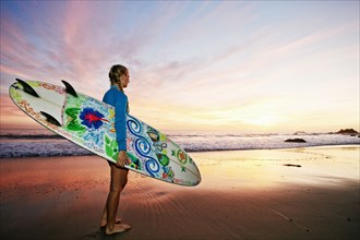 Caucasian woman carrying surfboard at beach