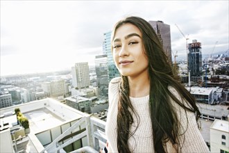 Smiling Hispanic woman posing on urban rooftop