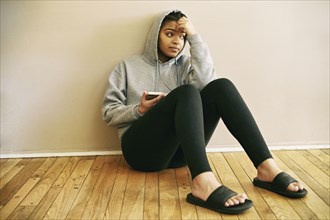 Mixed Race woman sitting on floor listening to cell phone