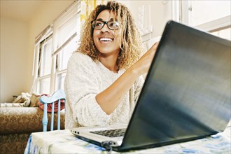 Smiling Mixed Race woman using laptop