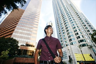 Smiling Mixed Race businessman near highrises in city