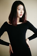 Asian woman posing in black dress with hands on hips
