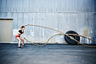 Mixed Race woman working out with heavy ropes outdoors