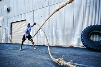 Black man working out with heavy ropes outdoors