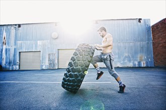 Caucasian man working out with heavy tire outdoors