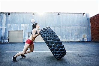 Caucasian woman working out with heavy tire outdoors