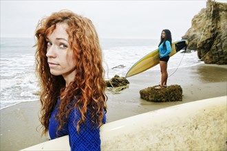 Serious women holding surfboards at beach