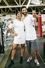 Mixed Race man couple posing for cell phone selfie in gymnasium