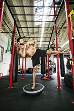 Mixed Race man standing on balance trainer in gymnasium