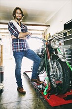 Caucasian man posing with motorcycle in garage
