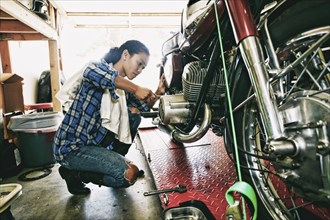 Mixed Race woman repairing motorcycle in garage
