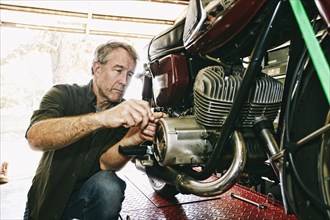 Caucasian man repairing motorcycle in garage