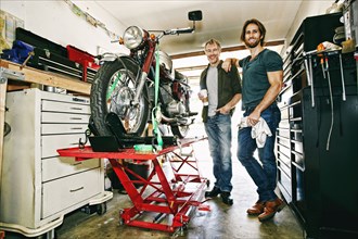 Caucasian father and son repairing motorcycle in garage