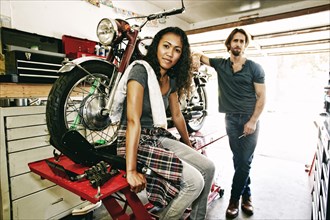 Serious man and woman posing with motorcycle in garage