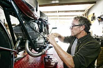 Caucasian man repairing motorcycle in garage