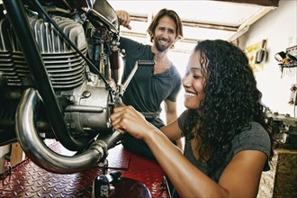 Man watching woman repairing motorcycle in garage
