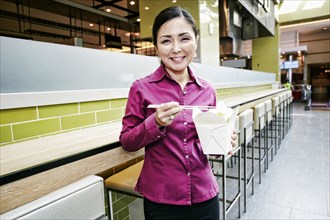Smiling Japanese businesswoman posing in food court