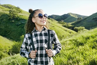 Smiling girl wearing backpack on hill