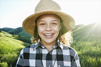 Smiling girl wearing hat on sunny hill