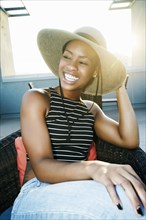 Black woman wearing sun hat on rooftop