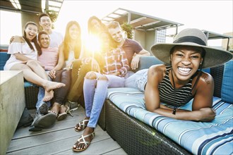 Portrait of smiling friends on rooftop sofa