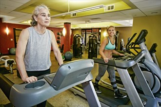 Caucasian mother and daughter on treadmills