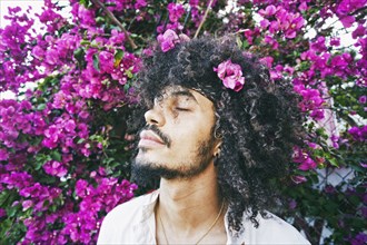 Portrait of Mixed Race man smelling flowers