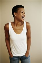 Portrait of laughing Black woman with hands in pockets