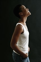 Black woman standing and laughing with hands in pockets