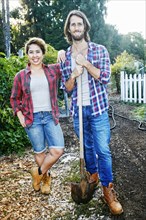 Portrait of couple posing with shovel in garden