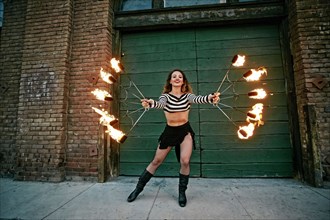 Caucasian woman juggling fire on city sidewalk