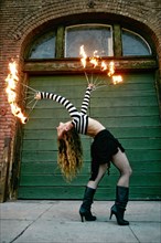 Caucasian woman juggling fire on city sidewalk