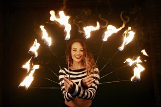 Caucasian woman juggling fire at night