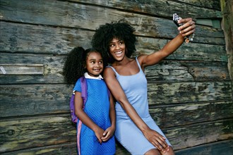 Black mother and daughter posing for cell phone selfie