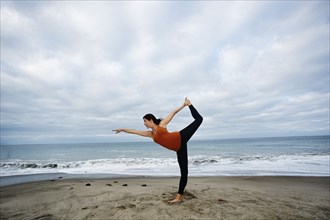 Caucasian woman performing yoga on beach