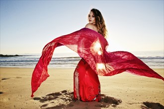 Caucasian belly dancer holding scarf on beach